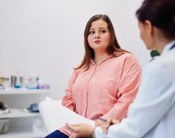 Ärztin spricht mit einer jungen übergewichtigen Patientin.