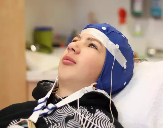 Junge mit Kappe für die Abnahme eines EEGs.