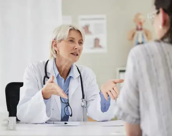 Ärtzin im Gespräch mit einer Patientin, die man von hinten sieht.