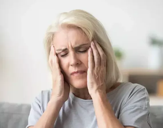 Frau hält sich die Schläfen - Kopfschmerzen.